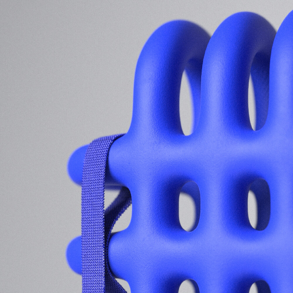 Close up of blue foam cage like object with strap hanging from it. Mega Mesh Backpack by All Design Lab.
