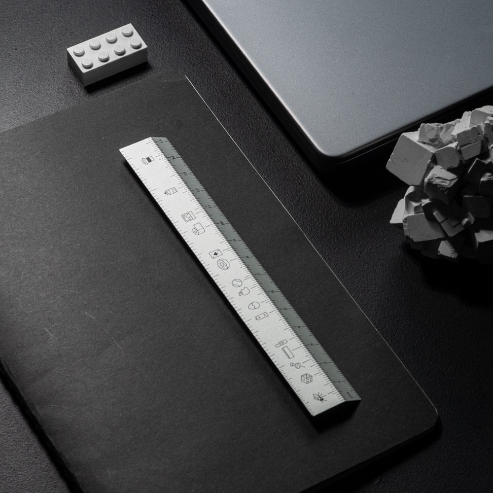 Metal ruler with icons on black notebook on black table. Ruler with icons by All Design Lab.